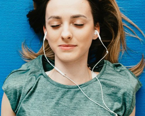 Frau mit Kopfhörer liegt entspannt - Enspannung im Alltag um sich beim Sex entspannen zu können