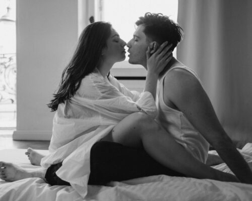 Paar sitzt im Bett und küsst sich beinahe