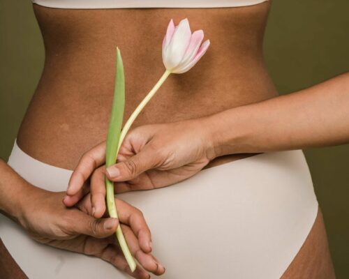 Rücken einer dunklen Frau hält Tulpe in der Hand