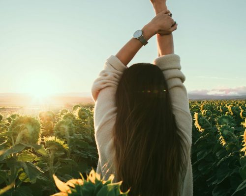 entspannte Frau in einem Sonnenblumenfeld, Enstpannung für mehr Lust auf Sexualität